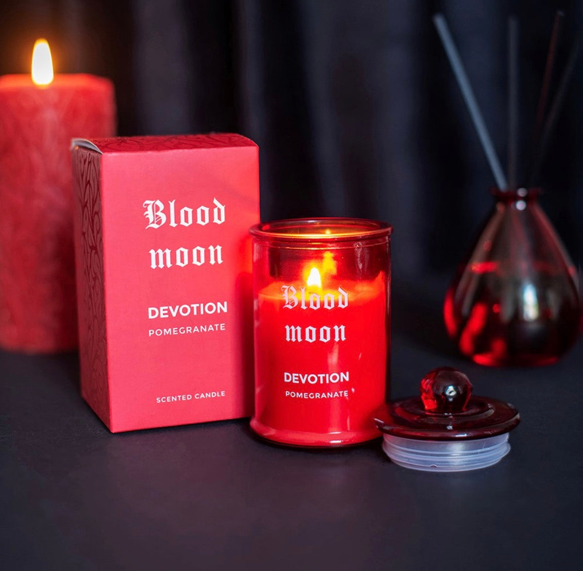 Blood Moon pomegranate candle glowing beside its gift box