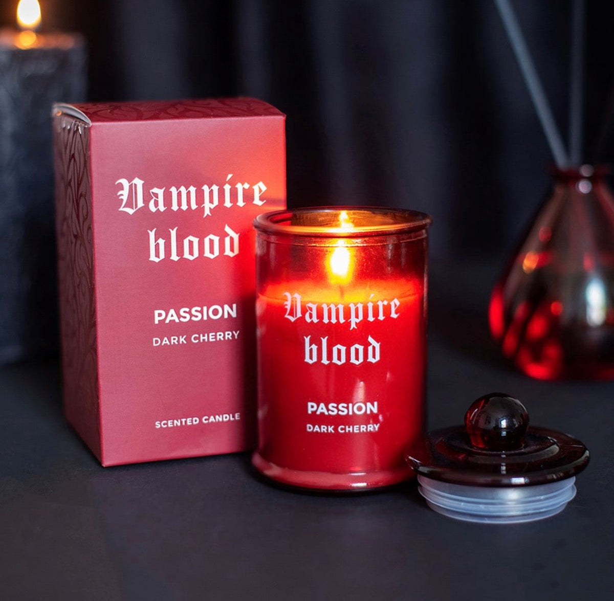 Vampire Blood dark cherry candle glowing beside its gift box