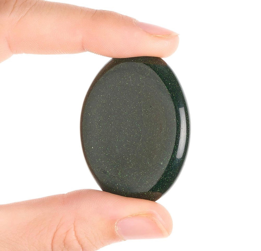 Green Goldstone worry stone shown between fingers for scale
