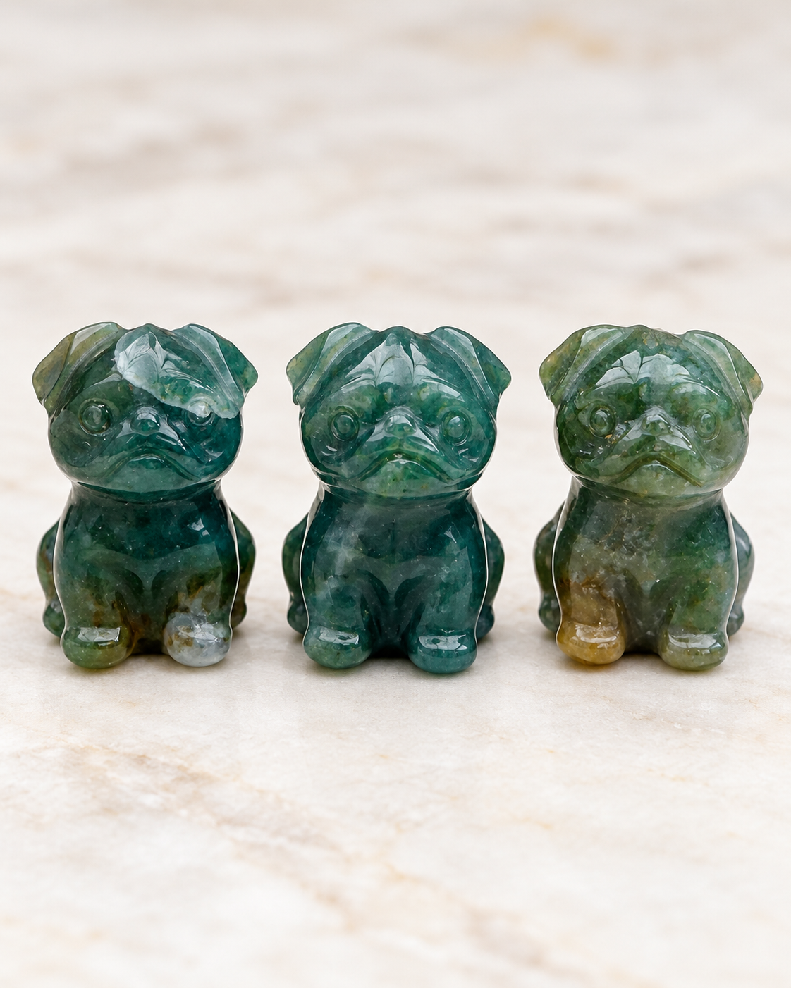 Three Moss Agate mini crystal pug carvings showing natural variation