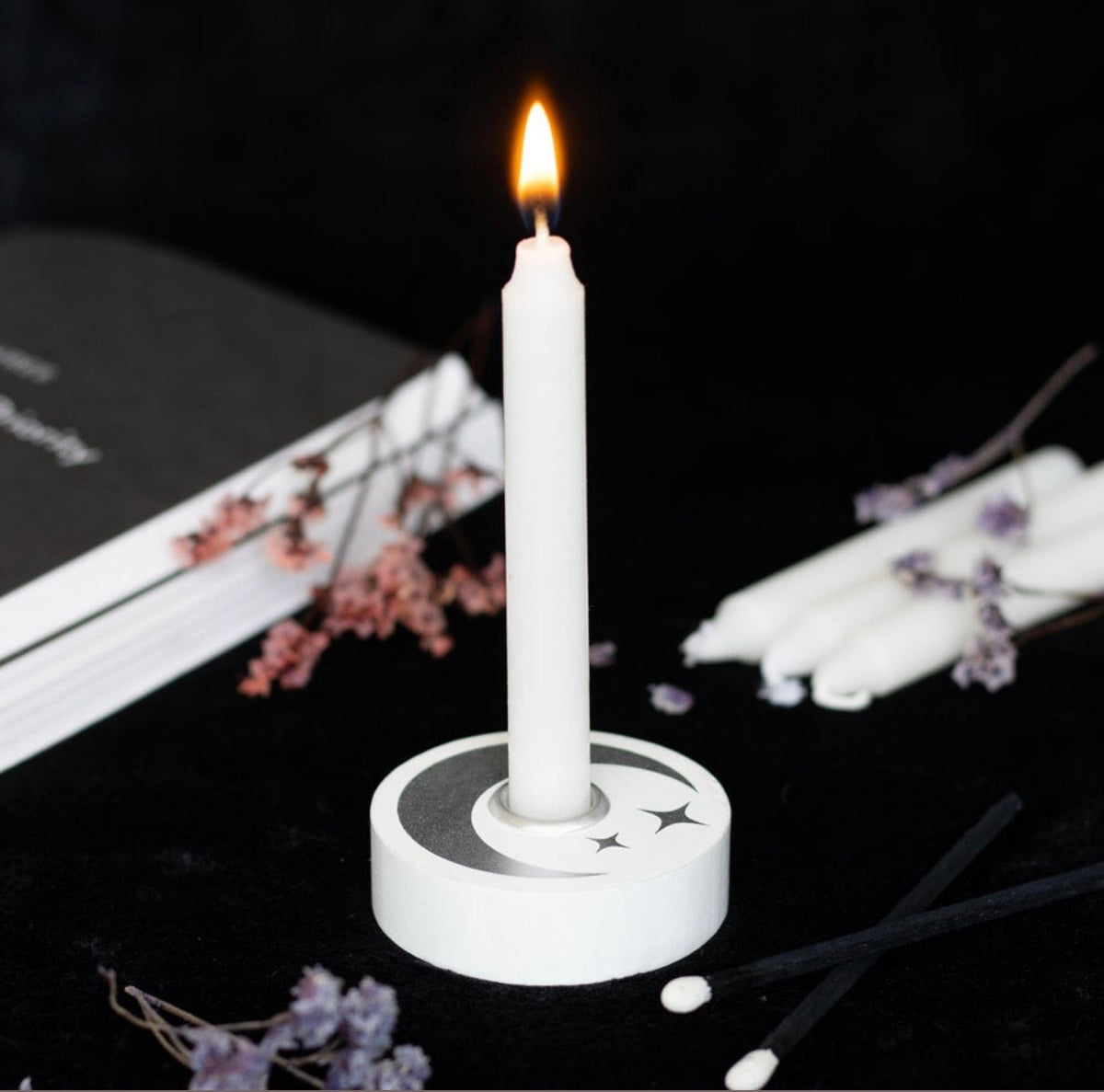 Mystical moon spell candle holder with a lit white candle in a styled ritual setting