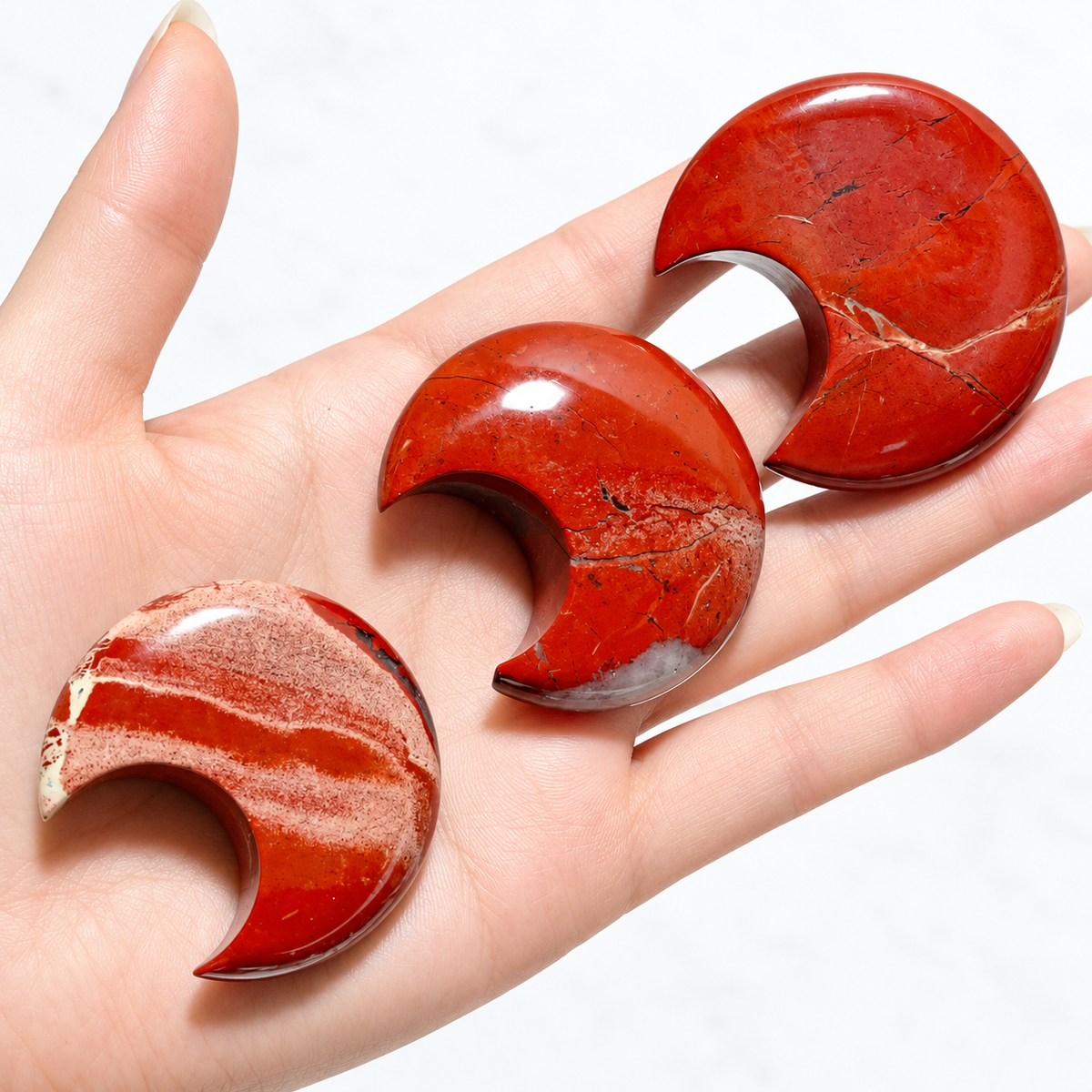 Red Jasper crescent moons shown in hand for scale
